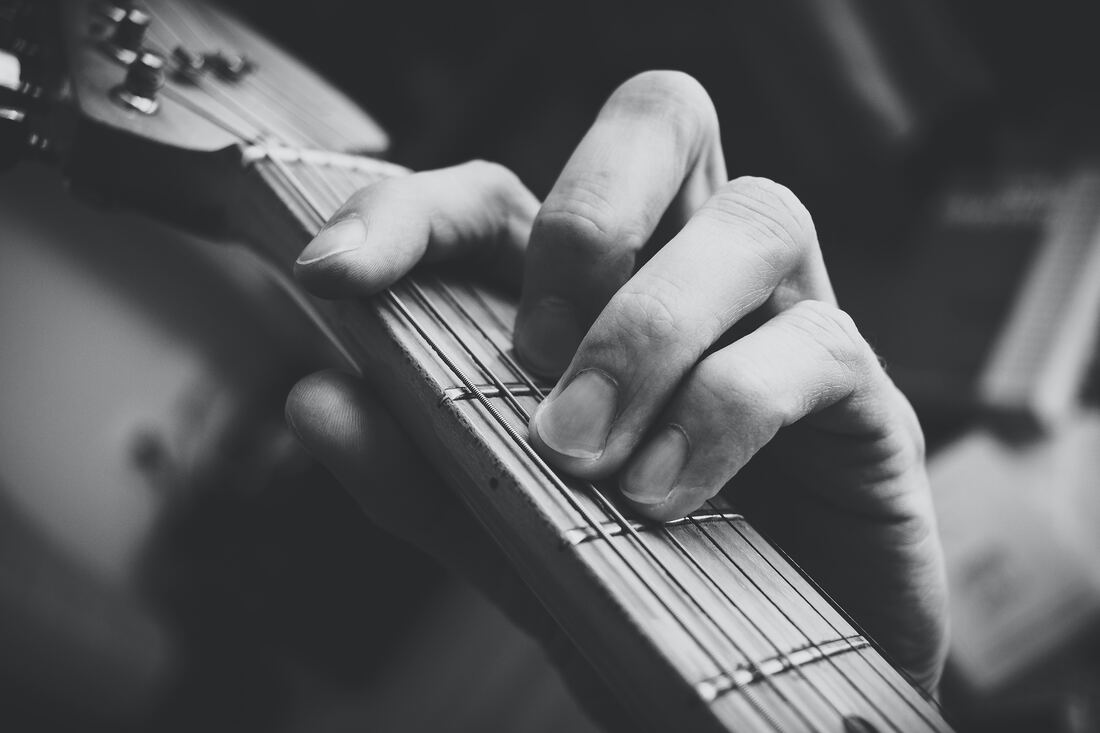 A close up of a hand playing a guitar chord in black and white