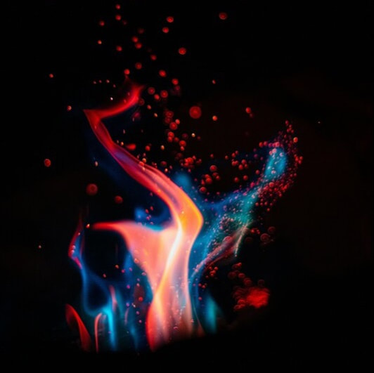 A chemical reaction in front of a black background producing blue, green, red, orange and yellow flame