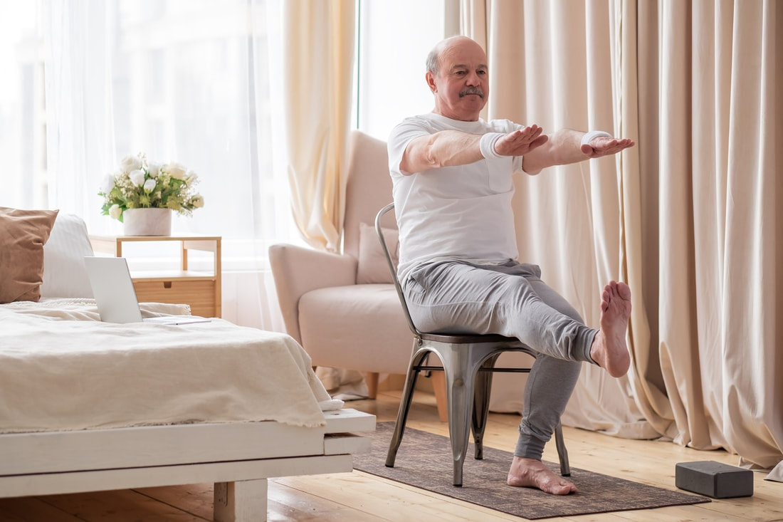 a senior practicing gentle yoga in a chair at home